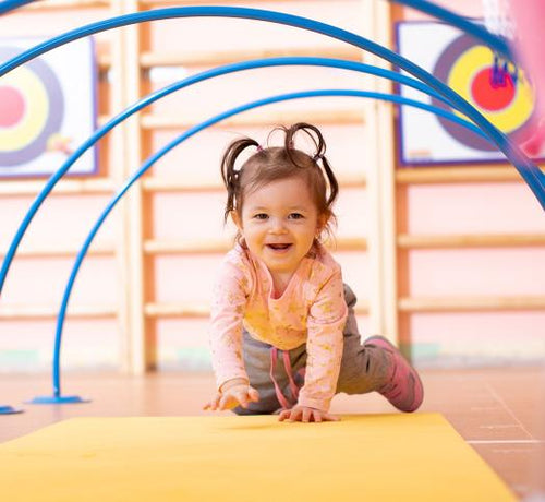 Enfant fille marchant à quatre pattes sur un tapis d'éveil jaune - Mustela Belgium - 1