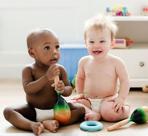 Deux bébés assis jouant avec des maracasses - Mustela Belgium - 1