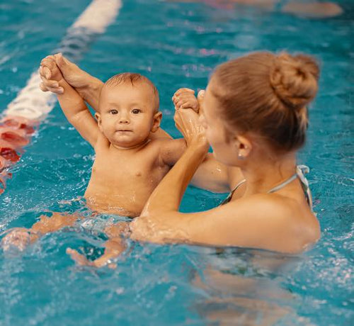 Bébé dans une piscine tenu dans les mains par une femme - Mustela Belgium - 1