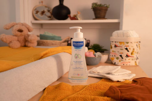 Sur la table à langer de bébé on y retrouve des lingettes en coton, une eau nettoyante Mustela et des changes - Mustela Benelux - 3