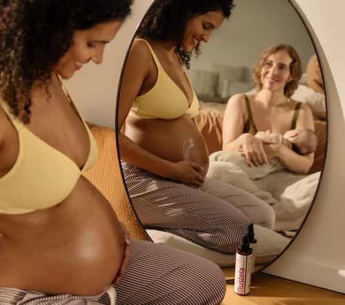 Une femme enceinte qui s'applique de la crème vergetures sur le ventre et une femme avec un bébé qui se regarde dans le mirroir - Mustela Benelux - 4
