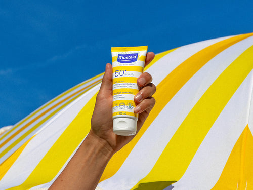 crème solaire tenu dans une mains plage - Mustela Benelux - 4