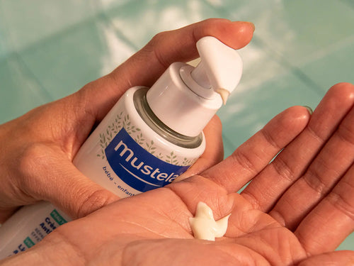 Un flacon avec pompe versant la crème pour atopie stelatopia mustela dans une mains - Mustela Benelux - 8